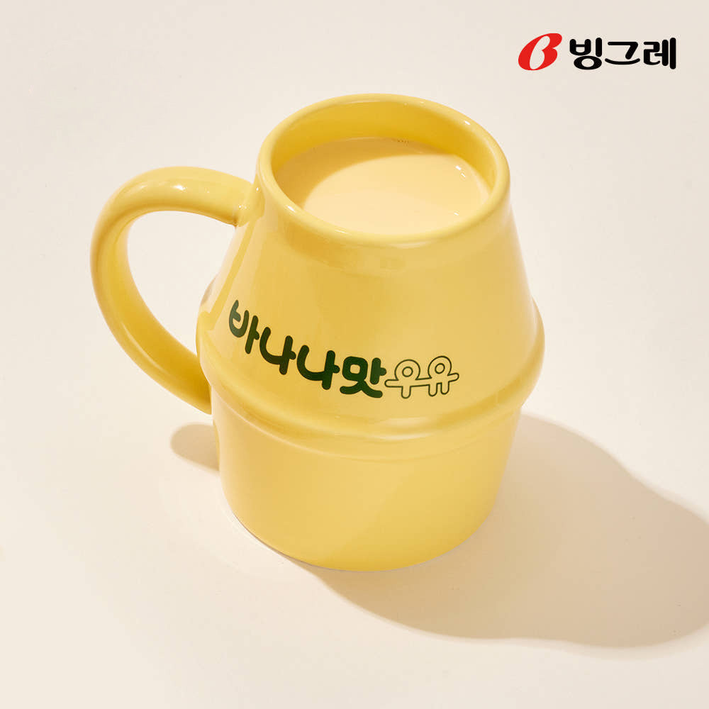 Close-up of a yellow Binggrae banana flavored milk ceramic mug with Korean lettering and ergonomic handle.