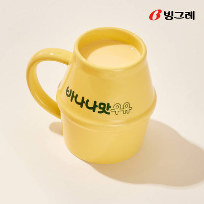 Close-up of a yellow Binggrae banana flavored milk ceramic mug with Korean lettering and ergonomic handle.