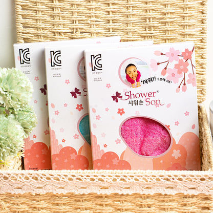 Korean exfoliating shower glove packages in basket with flowers